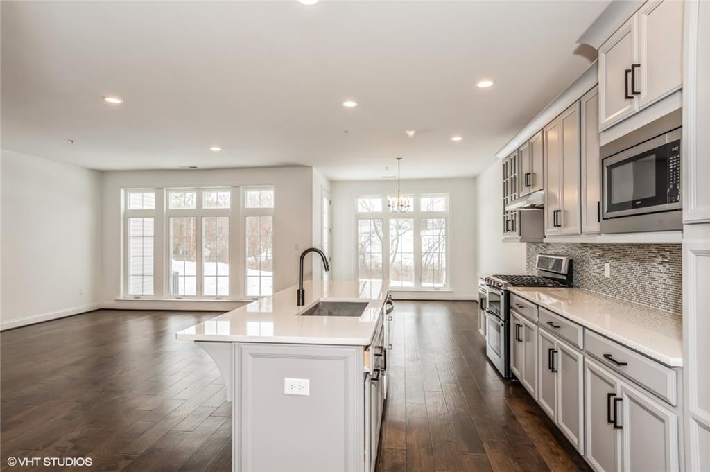 616 Gratitude Road Cranberry Township, PA 16066 - Photo 7 of 39 a kitchen with stainless steel appliances a stove top oven a sink a refrigerator white cabinets and wooden floor