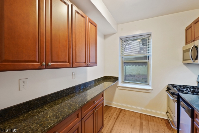 10 North Ridgewood Road, Unit 114 South Orange, NJ 07079 - Photo 4 of 15 a kitchen with granite countertop a sink a stove and wooden floor