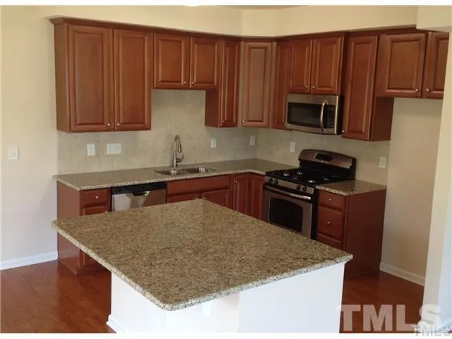 a kitchen with stainless steel appliances granite countertop a sink dishwasher microwave stove and refrigerator