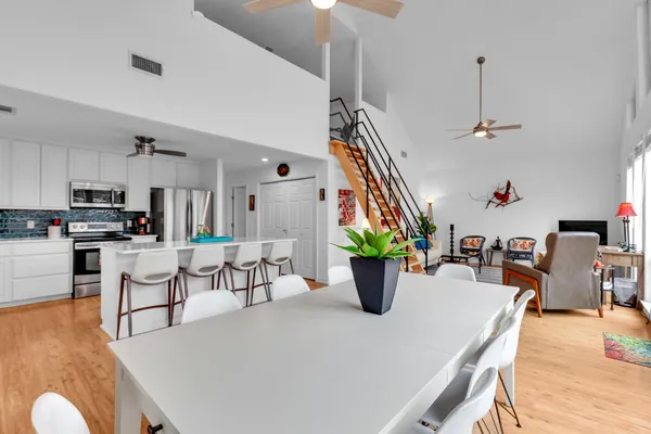 a kitchen with stainless steel appliances kitchen island granite countertop a refrigerator a stove a microwave oven a dining table and chairs with wooden floor