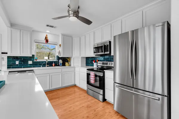 a kitchen with stainless steel appliances a refrigerator stove microwave and white cabinets