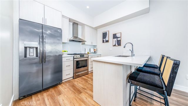 a kitchen with stainless steel appliances a sink a stove a refrigerator dining table and chairs