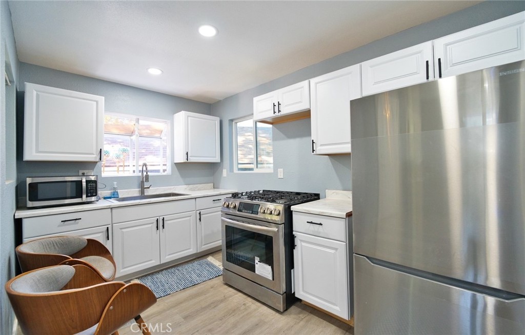 29083 Hook Creek Road Cedar Glen, CA 92321 - Photo 28 of 50 a kitchen with stainless steel appliances granite countertop a refrigerator a sink a stove and white cabinets