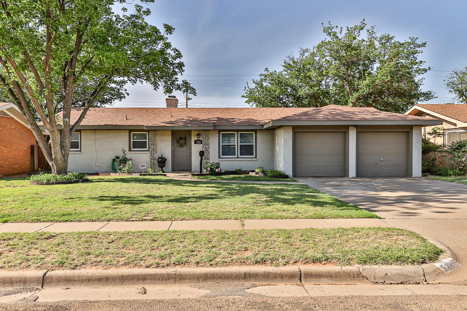 5221 14th Street Lubbock, TX 79416 - Photo 1 of 34 a view of a white house with a yard and large tree