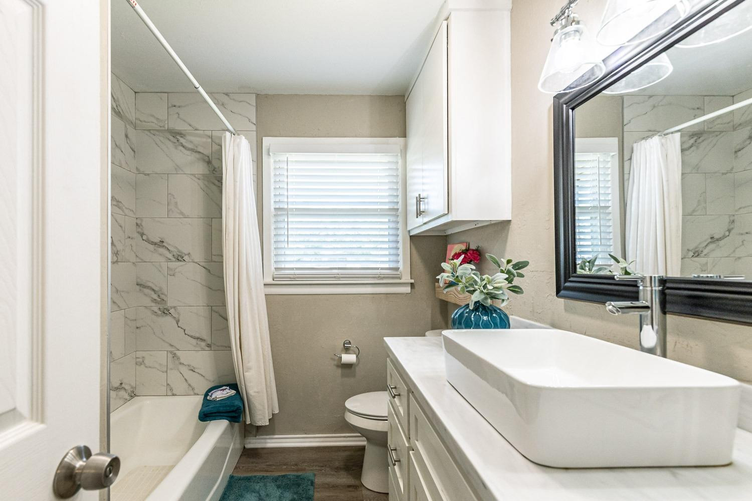 5221 14th Street Lubbock, TX 79416 - Photo 23 of 34 a bathroom with a granite countertop sink a toilet a tub and shower