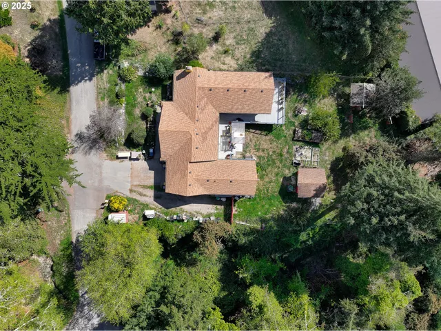 an aerial view of a house with a yard and trees all around