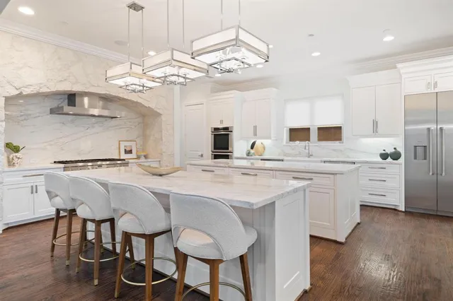 a kitchen with stainless steel appliances kitchen island granite countertop a table chairs and a refrigerator