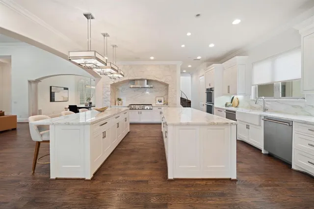 a large white kitchen with stainless steel appliances kitchen island a stove a sink a refrigerator a center island and a cabinets