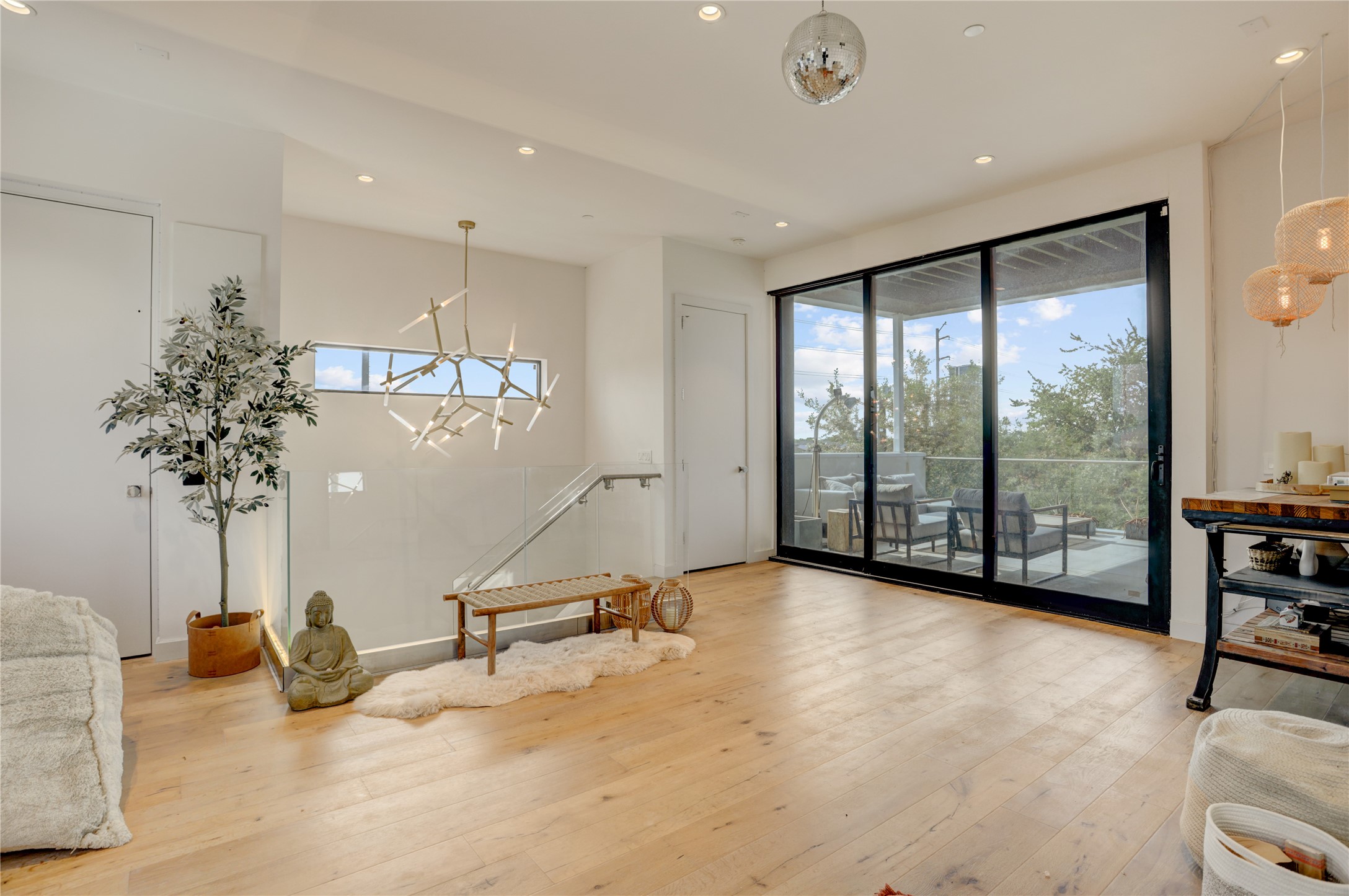 1807 Indiana Street Houston, TX 77006 - Photo 27 of 35 Fourth-Floor Bonus Room: Versatile top-floor lounge area featuring wide-plank wood flooring, custom designer lighting fixtures, and a massive sliding glass wall that opens entirely to the expansive rooftop deck.