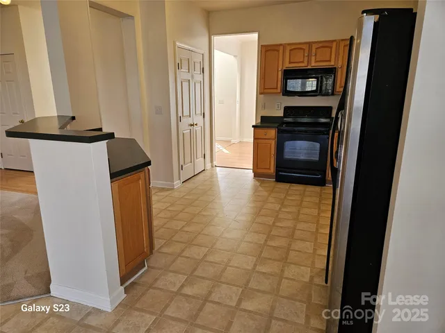 a view of a refrigerator in kitchen and an empty room
