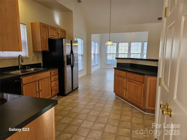 a kitchen with stainless steel appliances granite countertop a refrigerator a sink and wooden cabinets