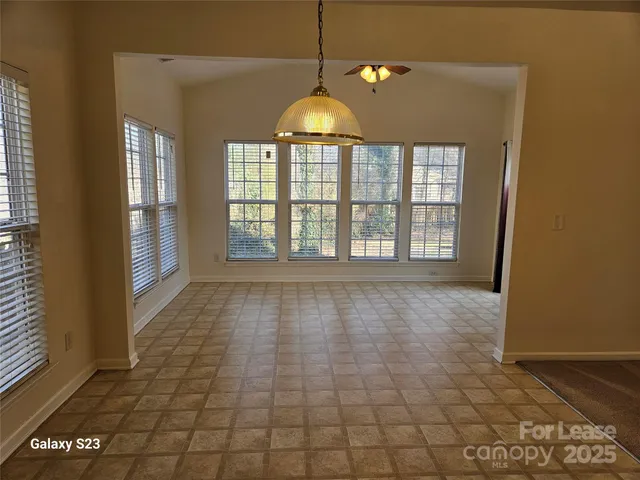 a view of an empty room with window and chandelier fan