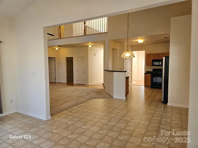 a view of a refrigerator in kitchen and an empty room