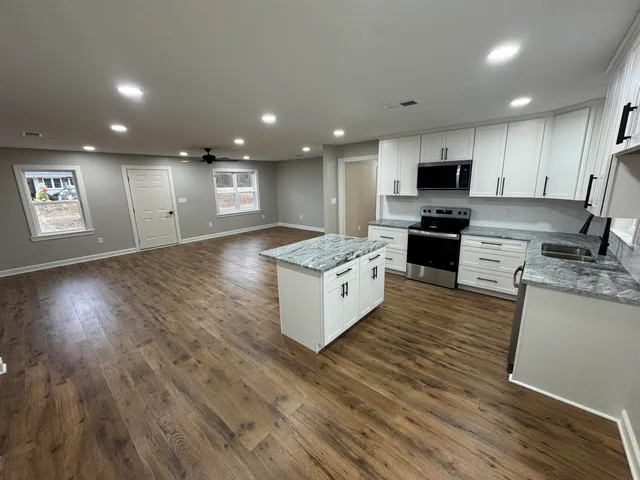 a large kitchen with stainless steel appliances granite countertop a large center island a stove a refrigerator and a sink