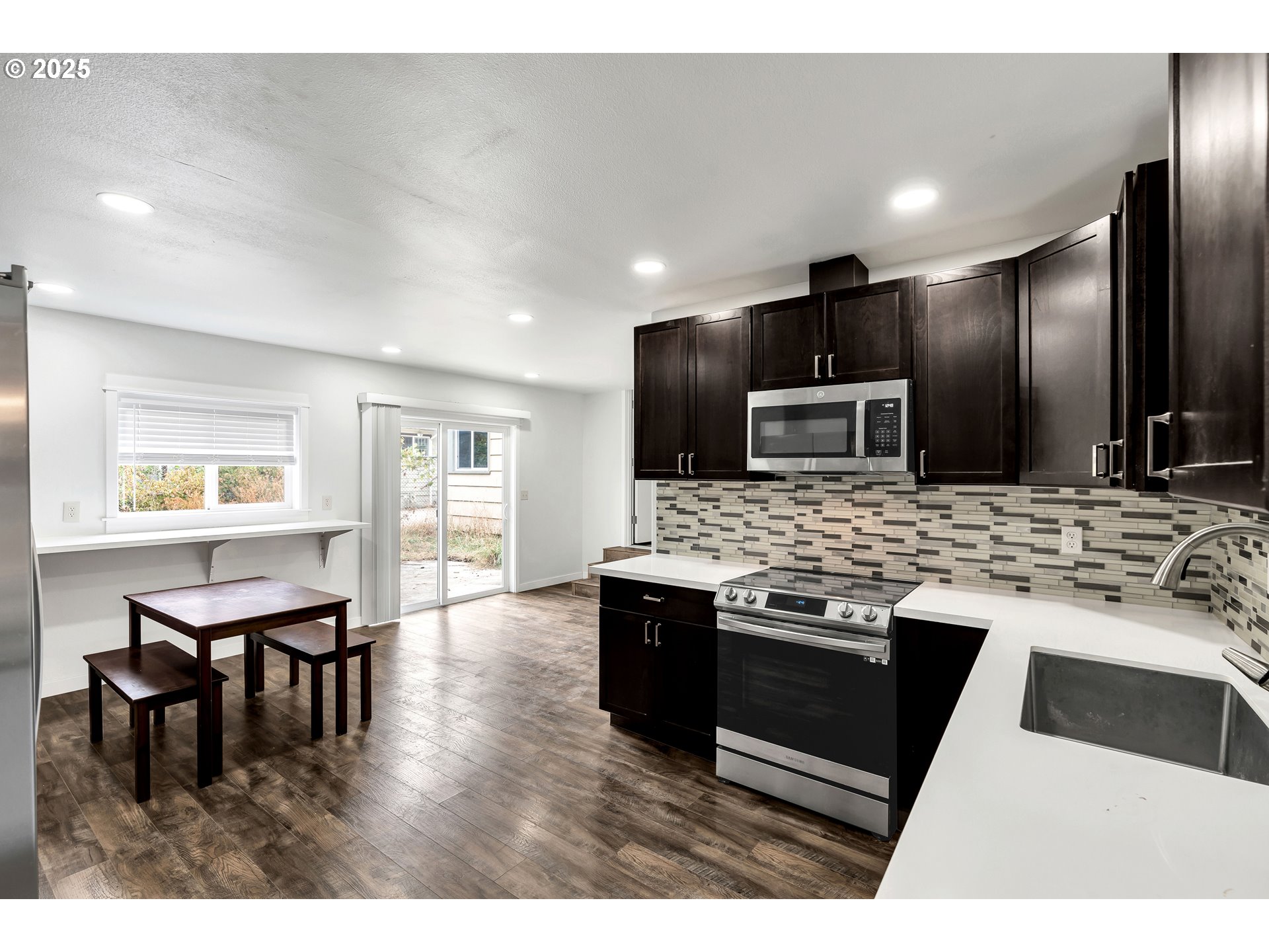 8451 Southeast Bush Street Portland, OR 97266 - Photo 17 of 47 a kitchen with stainless steel appliances kitchen island granite countertop a stove a refrigerator and a microwave