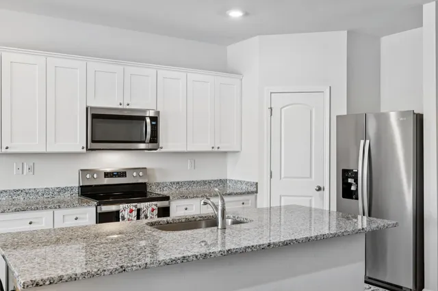 a kitchen with stainless steel appliances granite countertop a refrigerator and a stove top oven