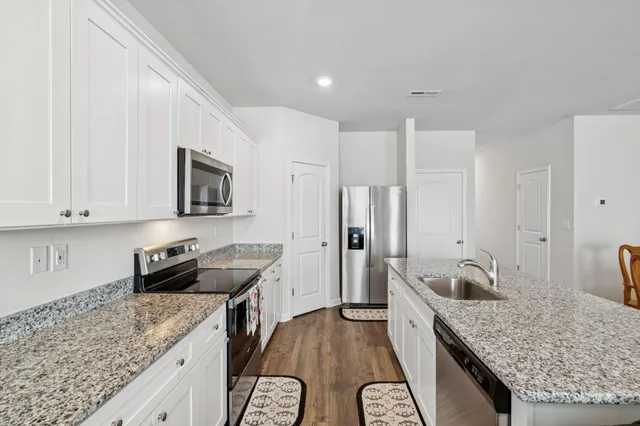 a kitchen with granite countertop a sink stove and refrigerator