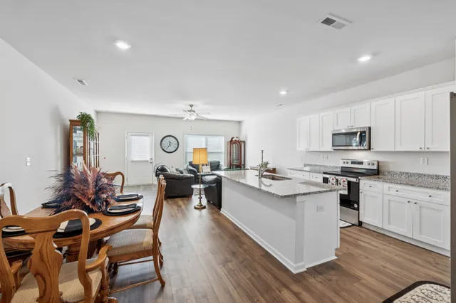 a living room with stainless steel appliances kitchen island granite countertop furniture a wooden floor and a sink