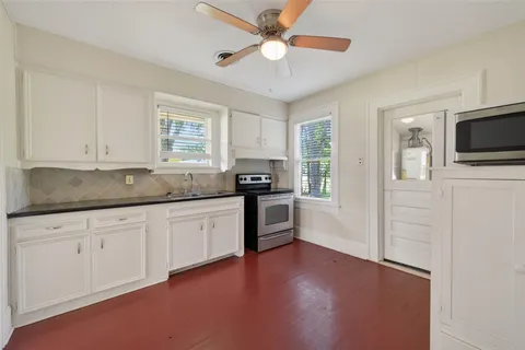 a kitchen with granite countertop white cabinets and black stainless steel appliances