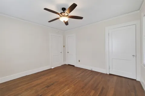 an empty room with wooden floor and ceiling fan