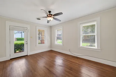 a view of an empty room with wooden floor and a window