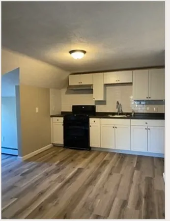 a large kitchen with granite countertop a sink and cabinets