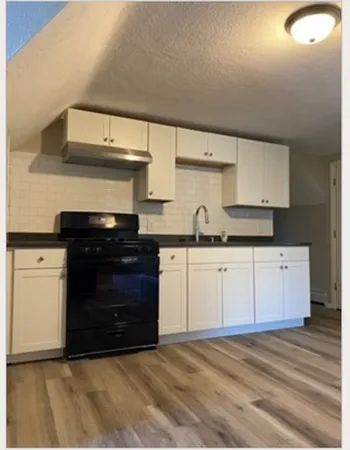 a kitchen with granite countertop a stove and cabinets