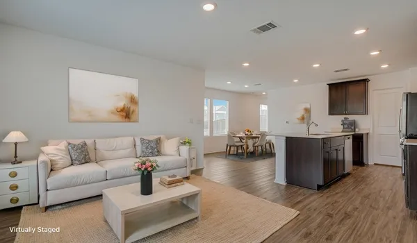 a living room with couches and kitchen view with wooden floor