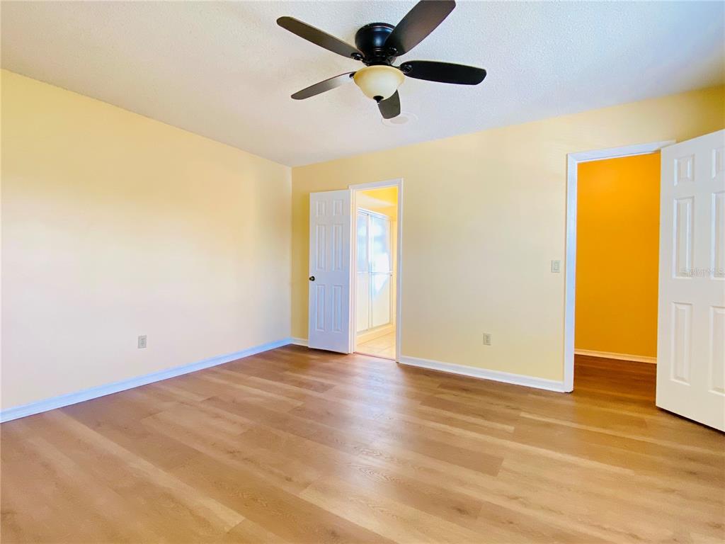 64 Windtree Lane, Unit 203 Winter Garden, FL 34787 - Photo 9 of 13 a view of an empty room with wooden floor and a ceiling fan