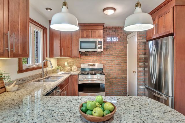 a kitchen with stainless steel appliances granite countertop a stove a sink and a refrigerator