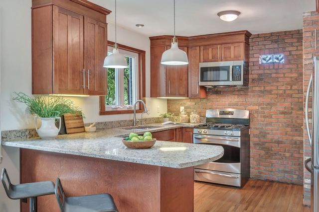 a kitchen with granite countertop a sink a stove and wooden cabinets