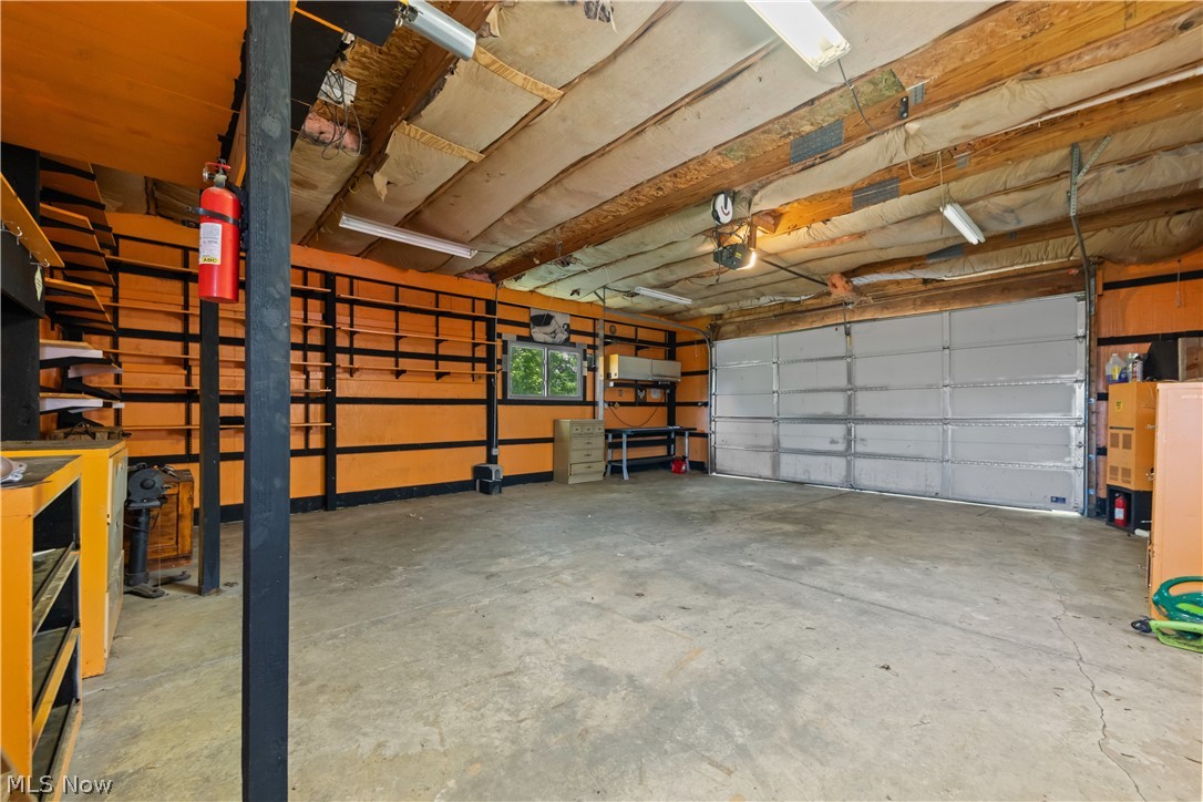 409 Edith Avenue Akron, OH 44312 - Photo 31 of 45 Spacious garage featuring a concrete floor, overhead fluorescent lighting, and a large roll-up garage door