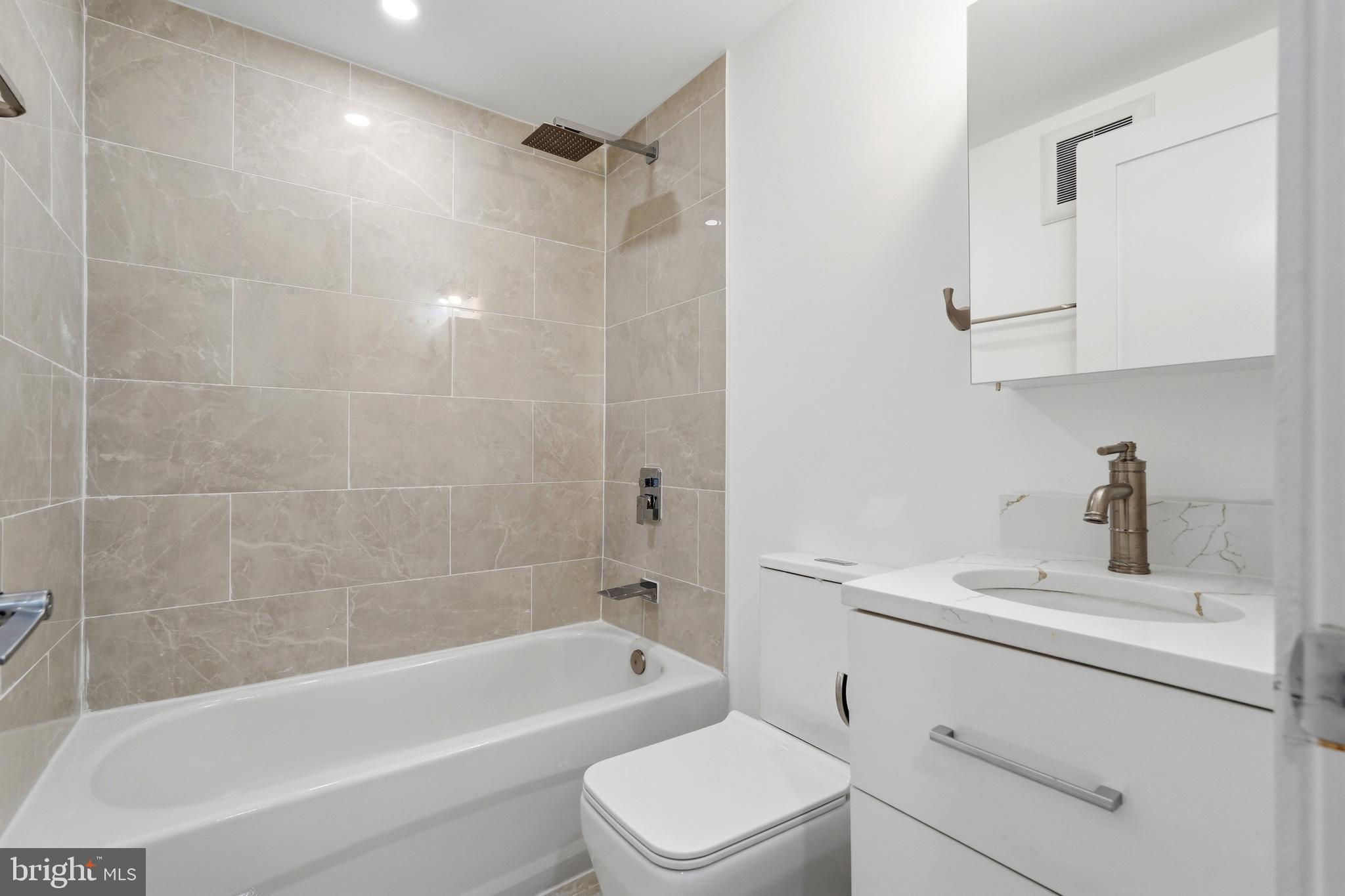 1810 Central Place Northeast, Unit 1 Washington, DC 20002 - Photo 23 of 36 a bathroom with a bathtub shower sink vanity and toilet