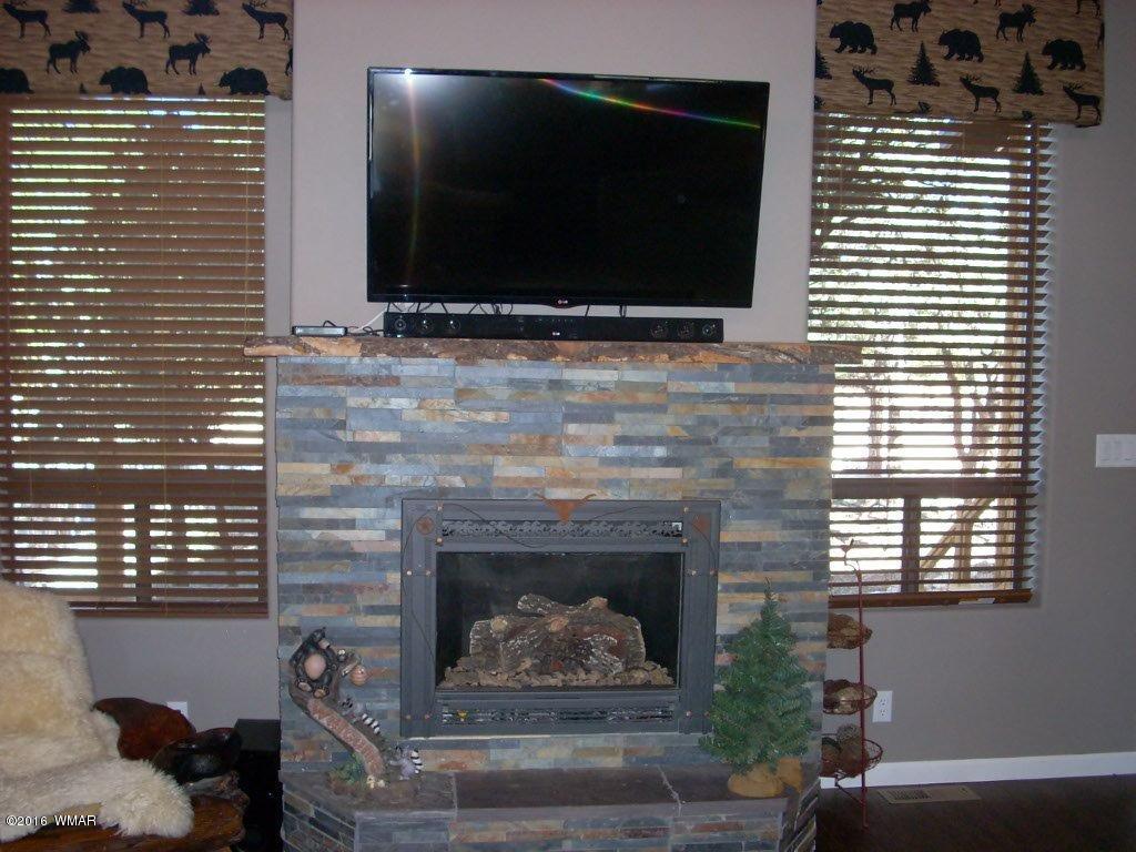 2975 East Lookout Lane Overgaard, AZ 85933 - Photo 5 of 34 a living room with a fireplace and a flat screen tv