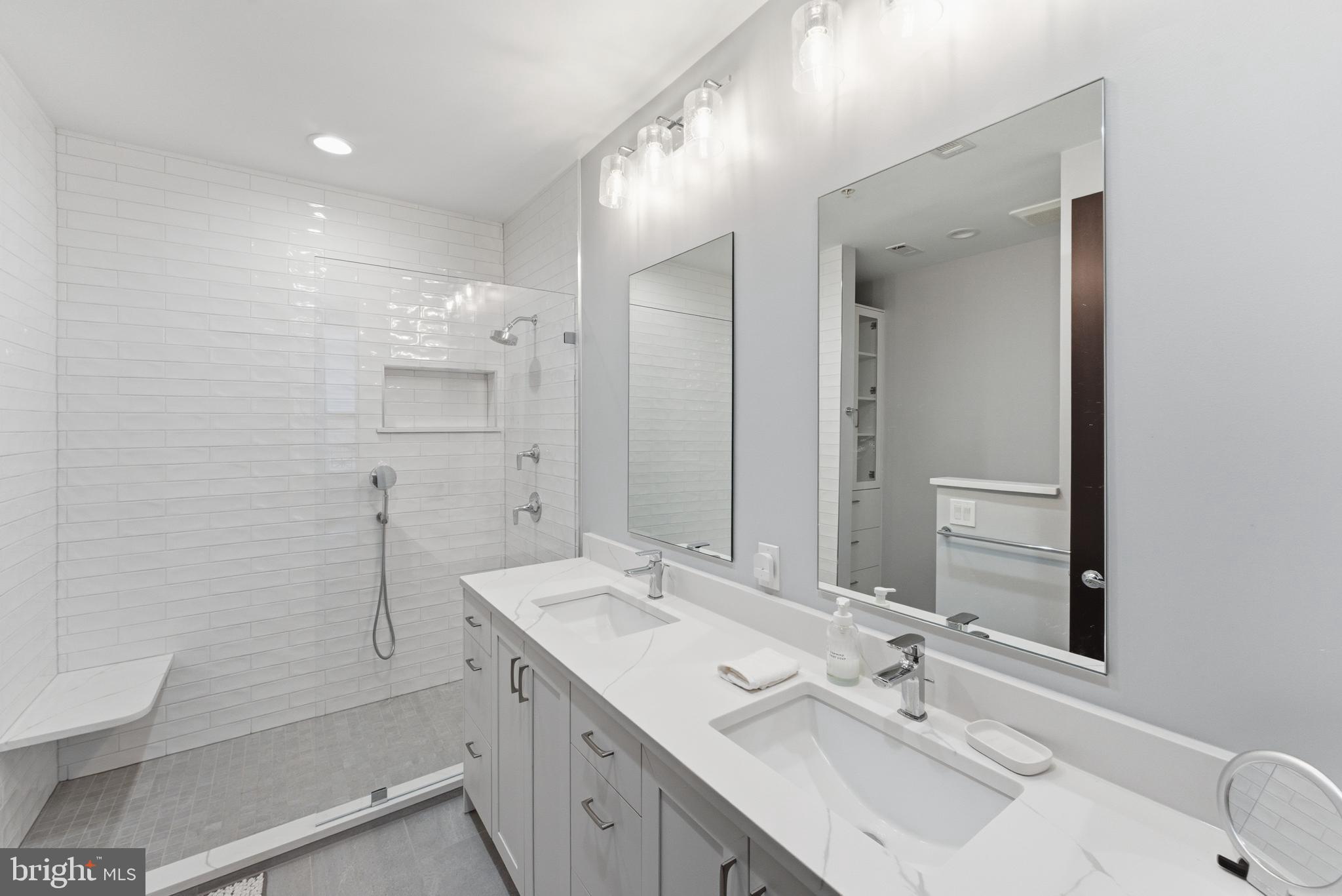 12025 New Dominion Parkway, Unit 103 Reston, VA 20190 - Photo 28 of 47 a bathroom with a sink double vanity granite tub shower and a mirror