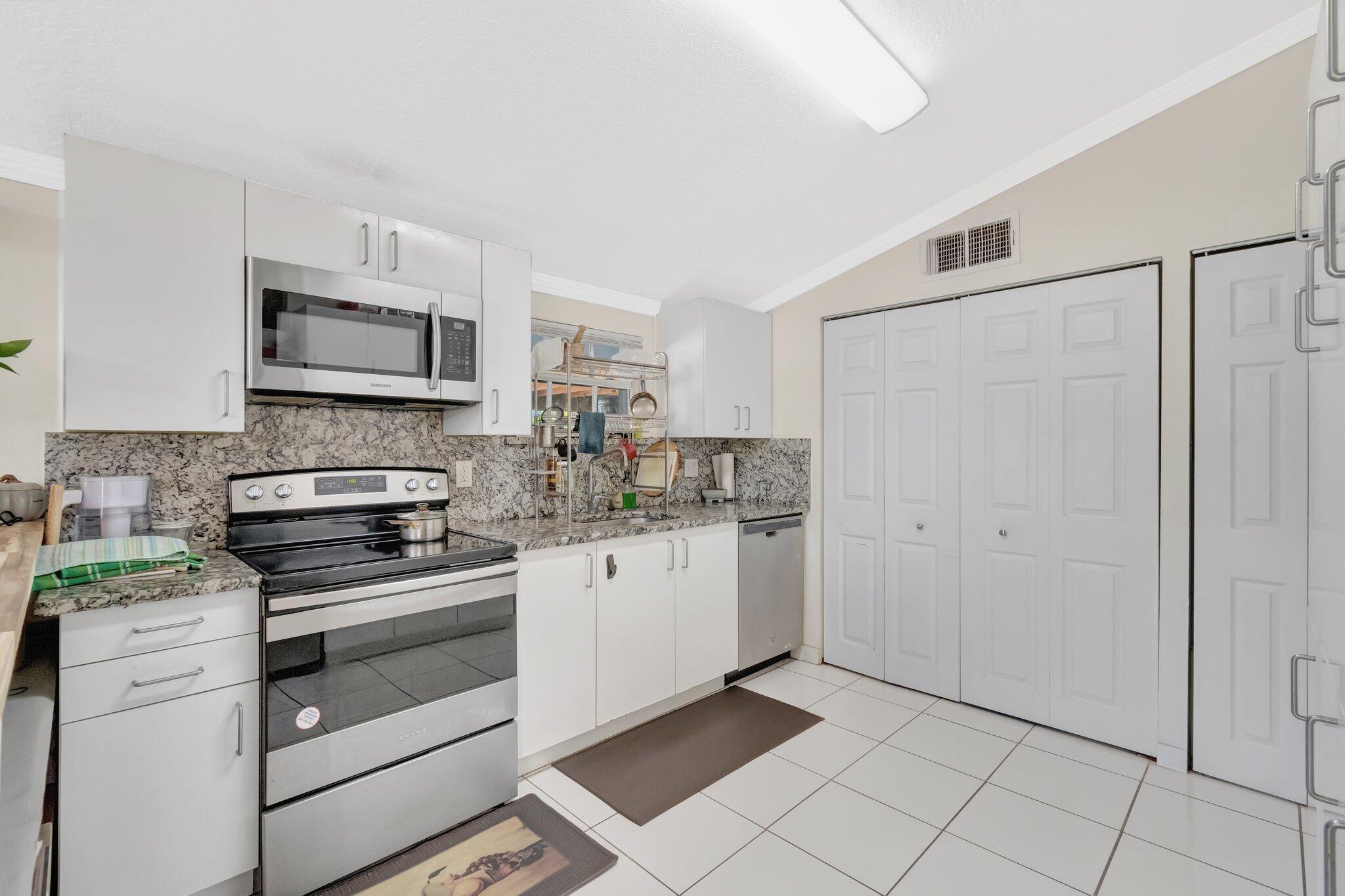 3935 Chickasha Road Atlantis, FL 33462 - Photo 15 of 44 a kitchen with granite countertop white cabinets stainless steel appliances and a counter space
