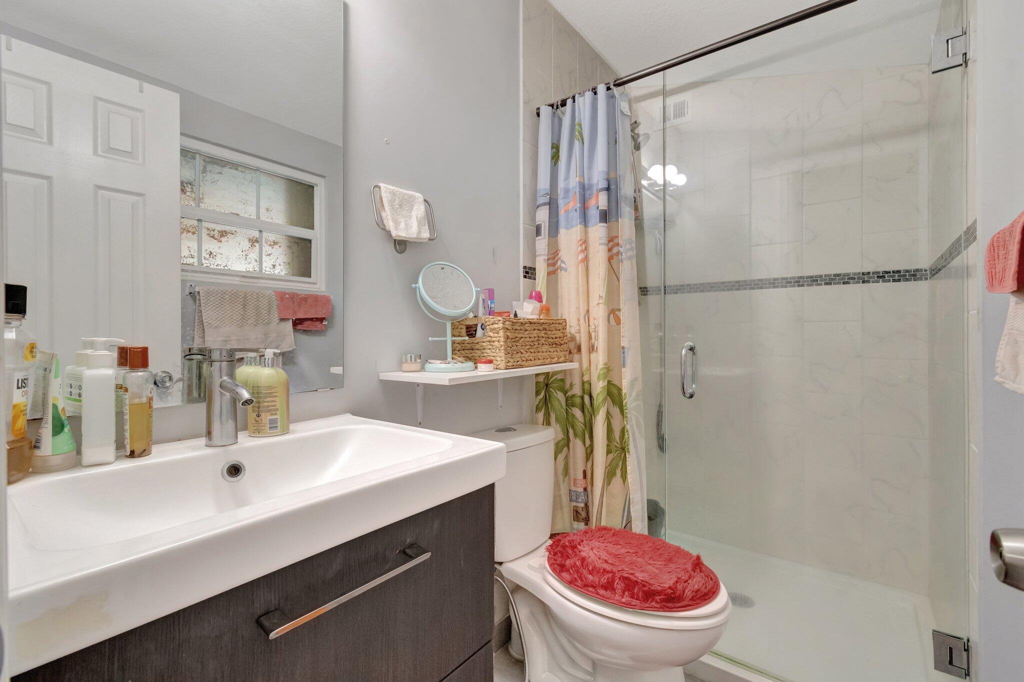 3935 Chickasha Road Atlantis, FL 33462 - Photo 22 of 44 a bathroom with a sink toilet mirror vanity and shower