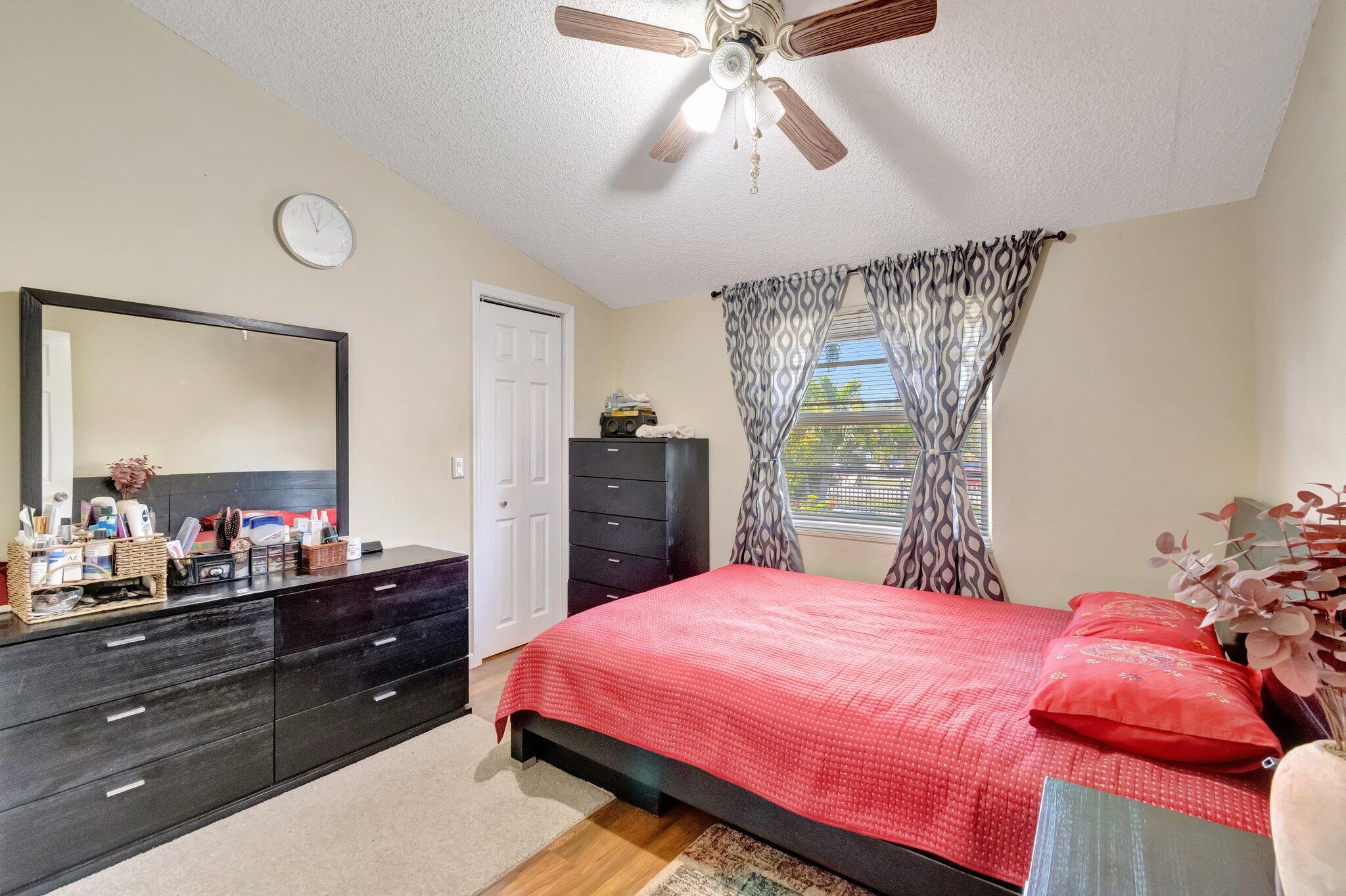 3935 Chickasha Road Atlantis, FL 33462 - Photo 25 of 44 a bedroom with a bed and a mirror on dresser
