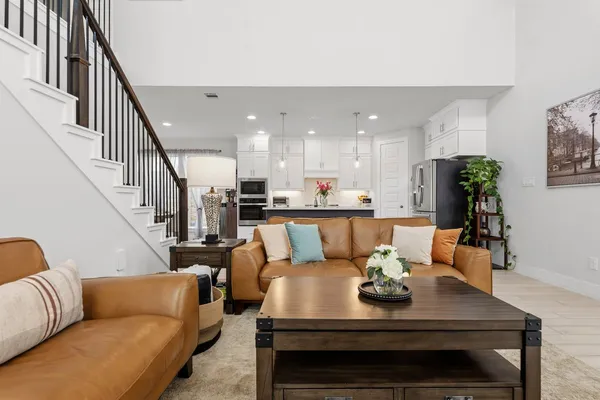 a living room with furniture kitchen view and a potted plant