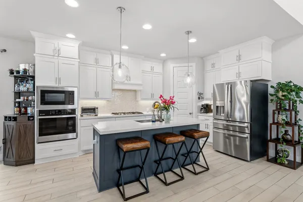 a kitchen with granite countertop a refrigerator oven a sink dishwasher and white cabinets with wooden floor