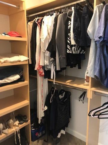 a view of walk in closet with clothes and shoes