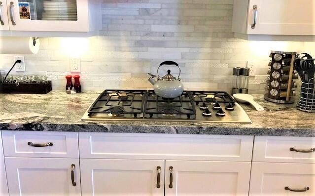 a kitchen with granite countertop white cabinets and a stove