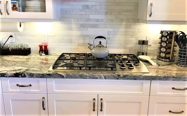 a kitchen with granite countertop white cabinets and a stove