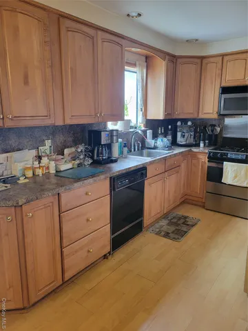 a kitchen with granite countertop white cabinets stainless steel appliances a sink and window