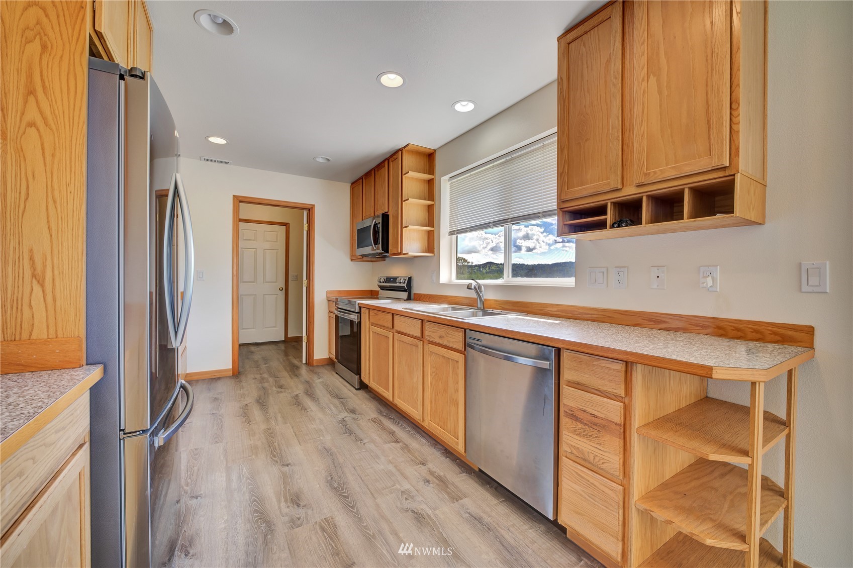 12112 Roosevelt Road Snohomish, WA 98290 - Photo 23 of 36 a kitchen with stainless steel appliances granite countertop a refrigerator a sink dishwasher and white cabinets with wooden floor