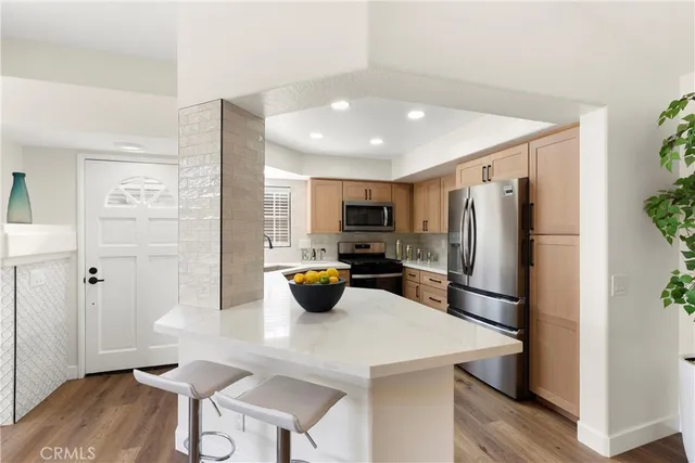 a kitchen with stainless steel appliances a refrigerator a stove a dining table and chairs