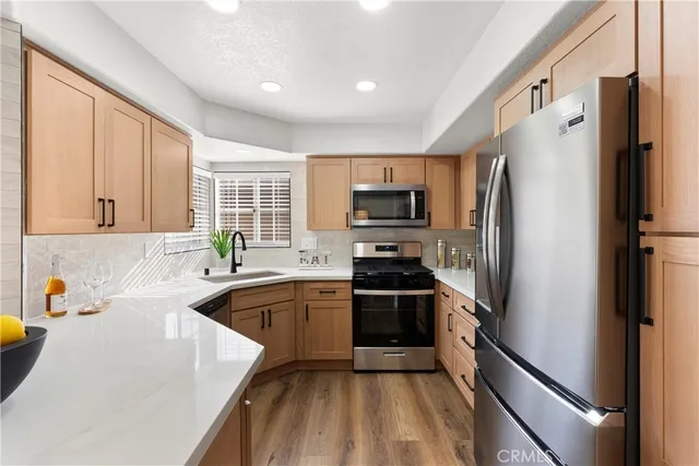 a kitchen with a refrigerator a sink a stove top oven and cabinets