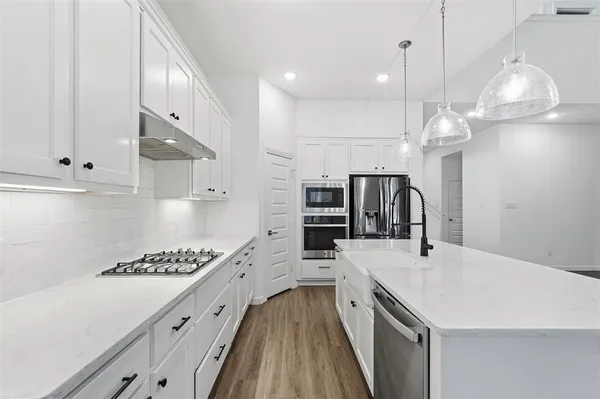 a kitchen with kitchen island stainless steel appliances a stove center island a oven a counter space and cabinets