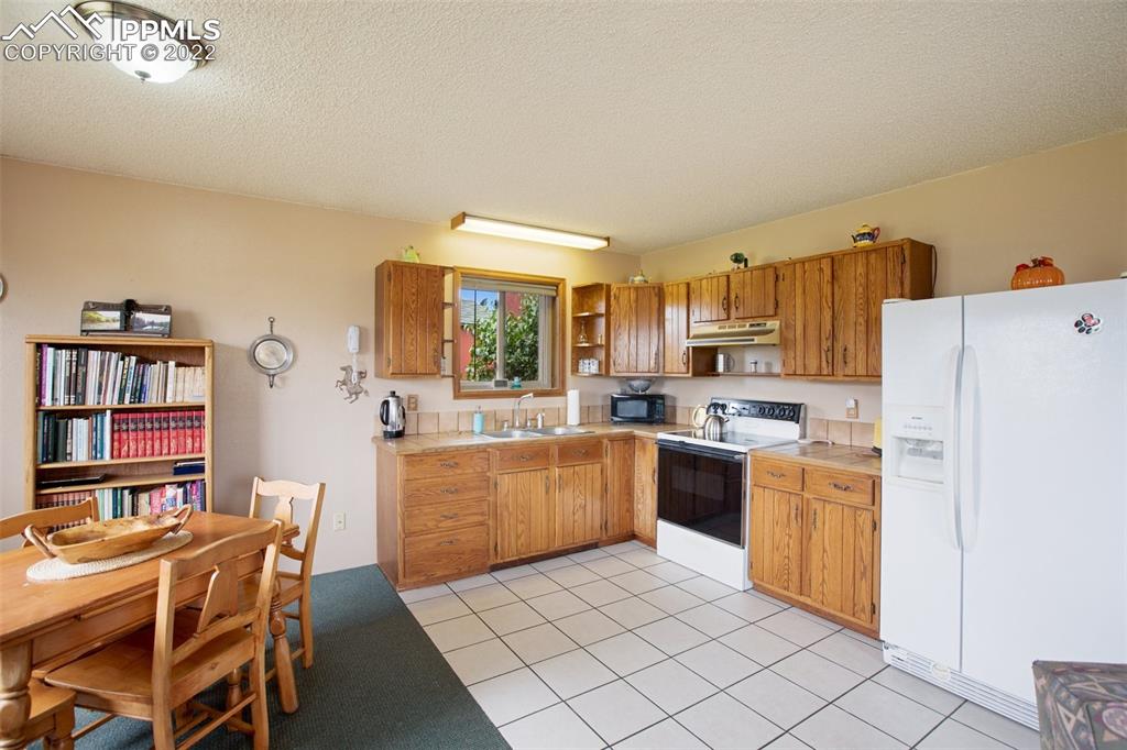 12 Ridge Drive Divide, CO 80814 - Photo 33 of 49 a kitchen with a refrigerator a stove top oven a dining table and chairs