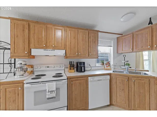 a kitchen with stainless steel appliances granite countertop a sink a stove a refrigerator with white cabinets and wooden floor